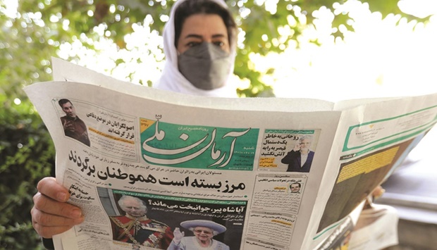 A woman reads the front page of the Iranian newspaper Arman, in a street in the Iranian capital. Tehran has avoided official comment on the death of Queen Elizabeth II, but some Iranians expressed outright hostility, accusing Britain of having supported the late Shahu2019s regime.