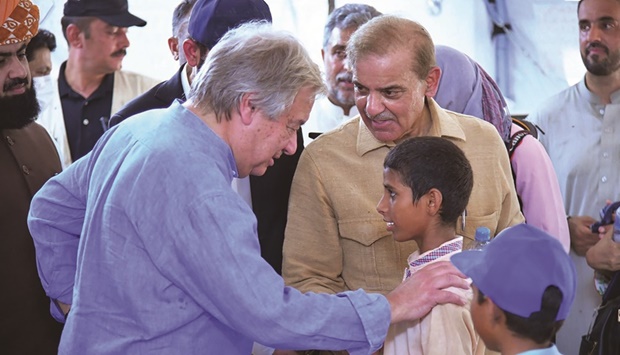 Pakistanu2019s Primer Minister Shehbaz Sharif (right) and UN Secretary-General Antonio Guterres (left) meeting internally displaced children at a makeshift camp during their visit to flood-affected Usta Mohamed city in Jaffarabad district in Balochistan province. (AFP)