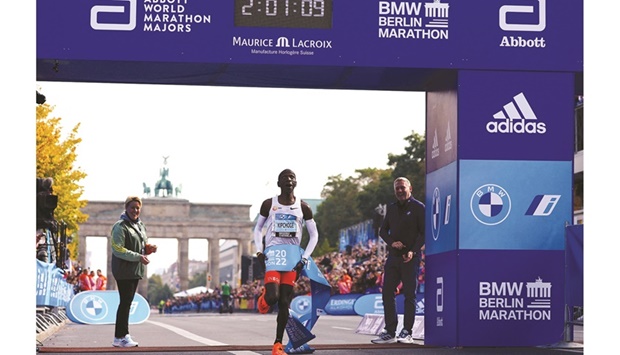 Kenyau2019s Eliud Kipchoge celebrates as he wins the Berlin Marathon yesterday. Below: Kipchoge celebrates on the podium  alongside elite womenu2019s race winner Ethiopiau2019s Tigist Assefa. (Reuters)