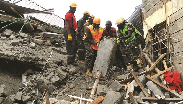 Members of the Disaster Rescue Unit (DRU) from the Kenya Defence Forces (KDF) remove debris of concrete at the scene of a collapsed building, blamed on poor construction materials in Kirigiti, Kiambu county, yesterday.
