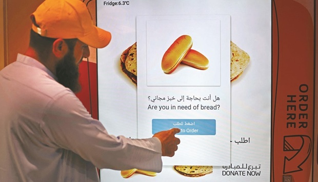A man orders items from a vending machine that gives out free bread, in Dubai.