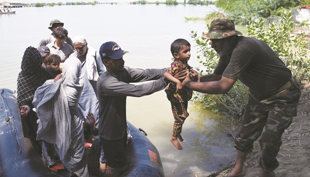 Pakistan Navy personnel pull flood victims from a boat after they were rescued from a flooded village, following rains and floods during the monsoon season in Khairpur Nathan Shah yesterday.