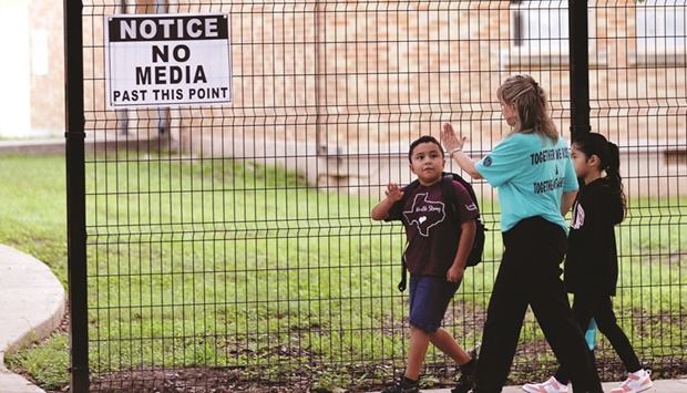 Students arrive at Uvalde Elementary School which has now been enclosed by a fence as they return after the summer break months after the Robb Elementary mass school shooting in Texas, yesterday.
