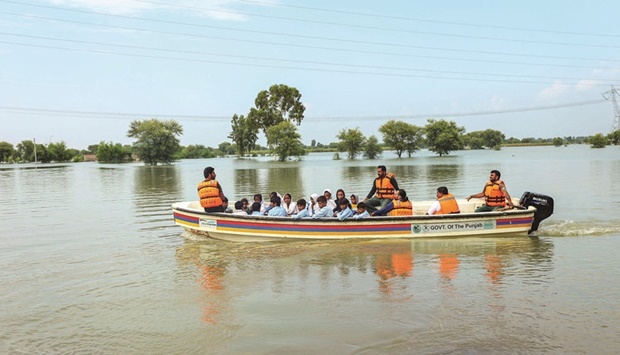 Rescue workers use a boat to drop children back home after school in a flood hit area following heavy monsoon rains in Dera Ghazi Khan district in Punjab province. (AFP)