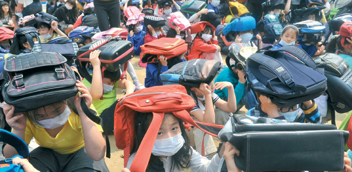 South Korean students hold their bags over their heads during an earthquake drill at an elementary school in Seoul yesterday. The 3-day u2018Safe Koreau2019 e