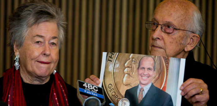 Juris Greste displays a picture of his son, jailed Australian Al Jazeera journalist Peter Greste, as his wife Lois looks on during a press conference 