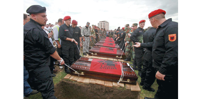  Ex-fighters of the Kosovo Liberation Army (KLA), wearing black uniforms of the former KLA, carry coffins of eight slain gunmen.