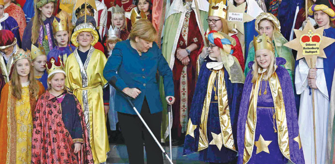Merkel stands with the aid of crutches among carol singers (Sternsinger) during a reception yesterday at the Chancellery in Berlin.