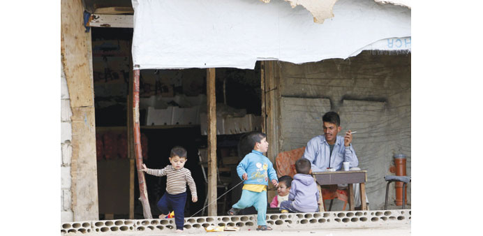 Children play beside a man resting inside a compound for Syrian refugees in Sidon, south Lebanon, yesterday.