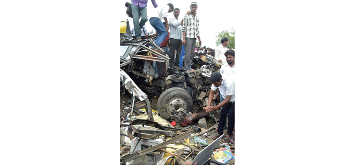 People stand on top of the bus wreckage in Medak district of Telangana yesterday. 