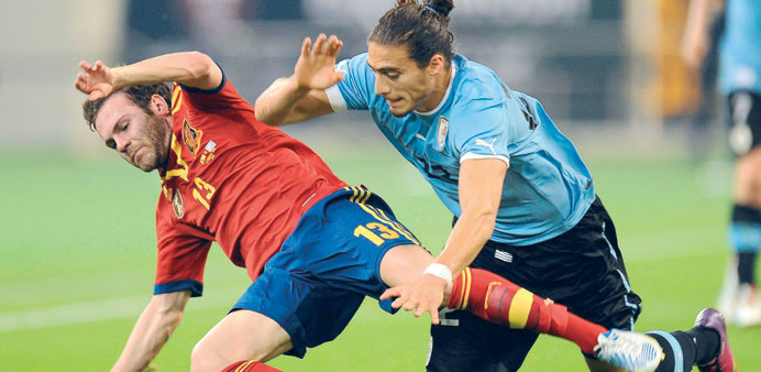 Juan Mata of Spain vies for the ball with Martin Caceres of Uruguay during the friendly at the Khalifa International Stadium in Doha, yesterday.