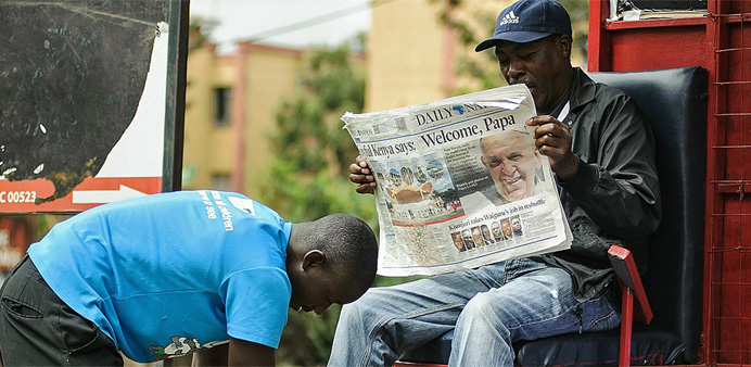 A man reads a newspaper carrying a headline about Pope Francis' visit to Africa in Nairobi