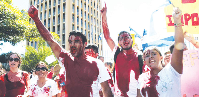 Anti-government protesters covered in artificial blood shout slogans during a protest against proposed reforms to the constitution put forward by Nica