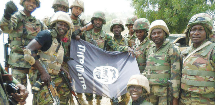 A Nigerian military handout picture of troops posing with a flag of Boko Haram after dismantling terrorists from their camp along Djimitillo Damaturu 