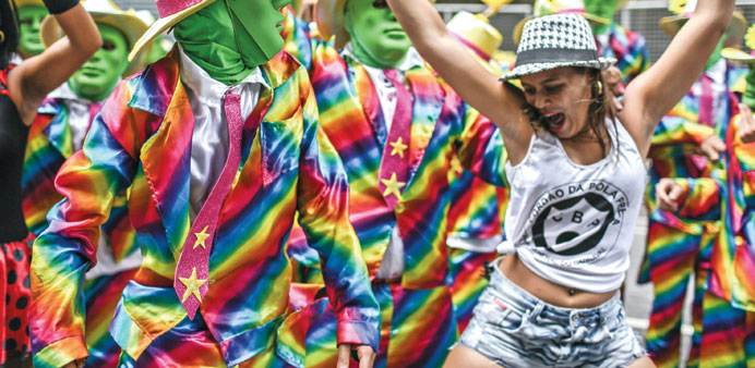A woman dances next to a dressed u2018comparsau2019 in the traditional march of u2018Cordao do Bola Pretau2019 group during the Carnival in Rio de Janeiro yesterday.