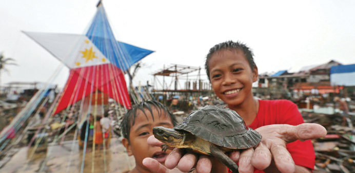 Filipino typhoon survivors Harold Yaras, 7, and John Magdua, 12 show a newly found turtle in front of a giant lantern in Tacloban.