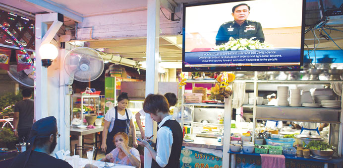 Thai army chief General Prayut Chan-O-Cha (centre) is seen making a speech on a television set as a waiter takes an order at a restaurant in Bangkok y