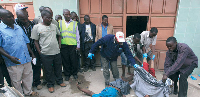  Kenyan police officers move the bodies of terror suspects killed during a shootout.