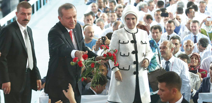 Turkish Prime Minister and president-elect Recep Tayyip Erdogan throws red carnations to AK Partyu2019s supporters, as his wife Emine Erdogan looks on, du