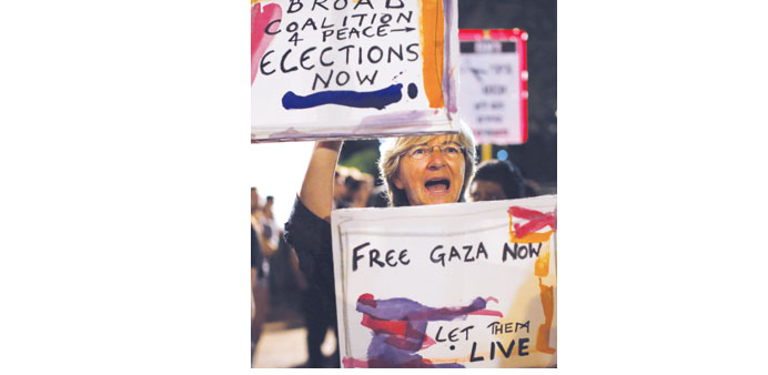 A supporter of peace holding placards shouting slogans as thousands of them gathered at the Rabin Square in Tel Aviv on July 26 to ask for the end of 