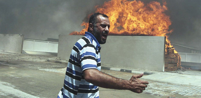 A Palestinian reacts in front of a fire which police said resulted from shelling by an Israeli tank in the industrial area in the east of Gaza City ye