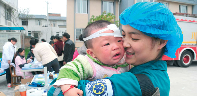 A Chinese medical worker holds an injured child in Longmen township, a town close to the epicentre of the earthquake.