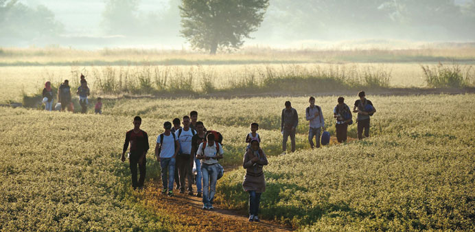 Migrants walking through a field to cross the border from Greece to Macedonia near the Greek village of Idomeni yesterday.