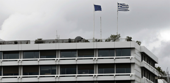 A European Union (L) and a Greek national flag flutter atop the Greek Finance Ministry in Athens 