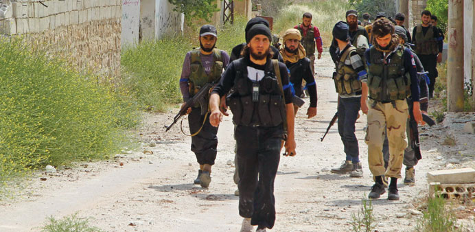 Rebel fighters walk in Al Mastumah village yesterday. 