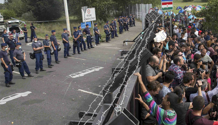 Migrants stand in front of a barrier at the border with Hungary near the village of Horgos, Serbia. Reuters