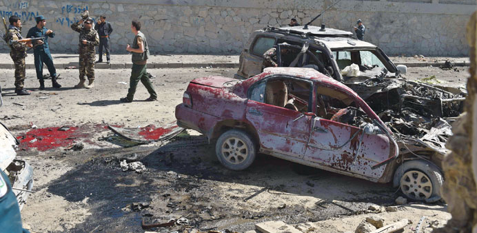 Afghan and foreign security forces inspect the site of a suicide attack in Kabul yesterday.