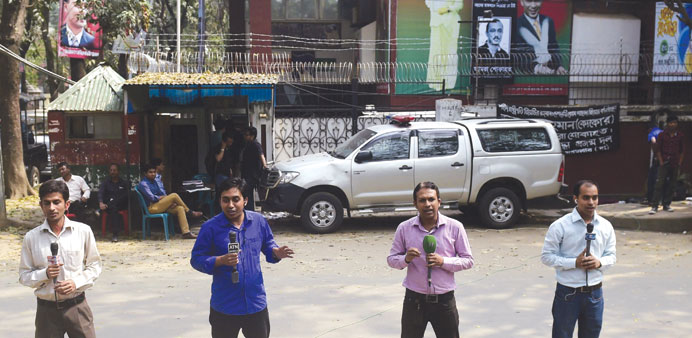 Bangladeshi television journalists report for their respective channels in front of the office of opposition Bangladesh Nationalist Party (BNP) leader