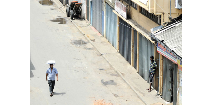 Sri Lankans are pictured on an empty street amid shuttered Muslim-owned shops, closed in protest following deadly communal violence in Colombo.