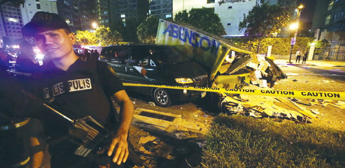 A Filipino policeman stands in front of a van damaged by debris from an explosion at a residential condominium in Taguig City, east of Manila yesterda