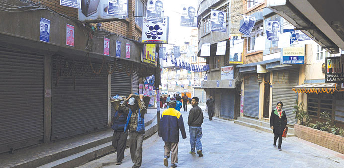 Pedestrians walking past closed shops during a general strike, called by the 33-party alliance and led by the Communist Party of Nepal-Maoist, in Kath