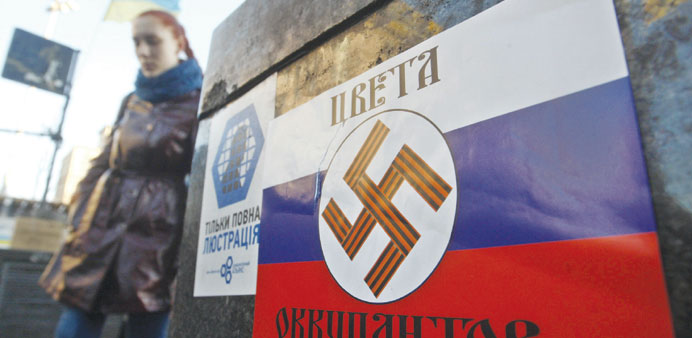 A girl walks past a poster with a Nazi swastika printed on a Russian flag and reading u2018Colours of the occupiersu2019 glued on Kievu2019s Independence Square.