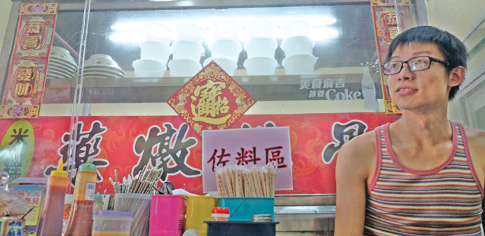 Carlos Cheung, a migrant from Hong Kong, poses in front of his food stall in central Taichung, Taipei.