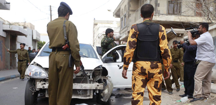 Policemen stand by a car damaged by the bomb blast in Sanaa yesterday.