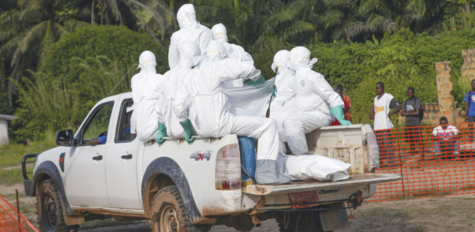 Liberian health workers carry the body of a woman who died of the Ebola virus from the isolation unit in Foya.