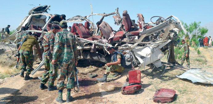 Pakistani security officials examine the destroyed vehicle used by security forces following a bomb attack on the outskirts of Quetta, the capital of 