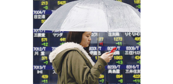 A woman walks past a share prices board in Tokyo. Japanese stocks ended marginally stronger at 15,534.82 points yesterday.