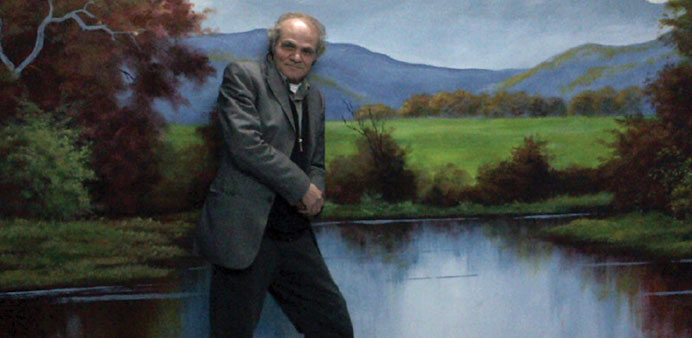 * Nader Haj Kadour poses with a landscape mural he did at a vocational high school in Reyhanli, Turkey.