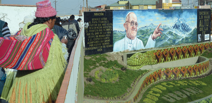 An indigenous woman walks past a mural of Pope Francis in El Alto, Bolivia.