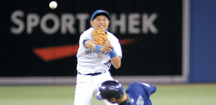 Toronto Blue Jaysu2019 Kawasaki throws to first base after putting out Colorado Rockiesu2019 Colvin to complete a game-ending double play in their MLB game in