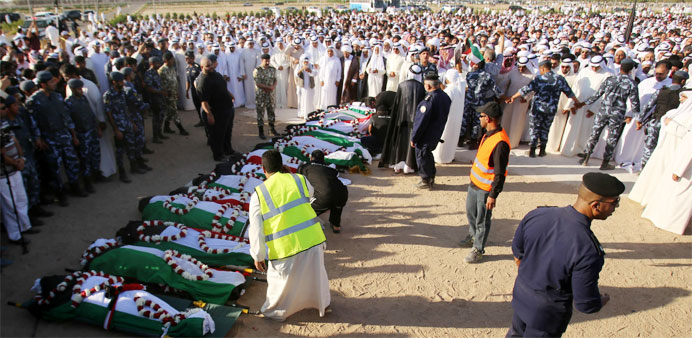 Mourners pray over the bodies of the victims of the Al-Imam Al-Sadeq mosque bombing, during a mass funeral at Jaafari cemetery in Kuwait City