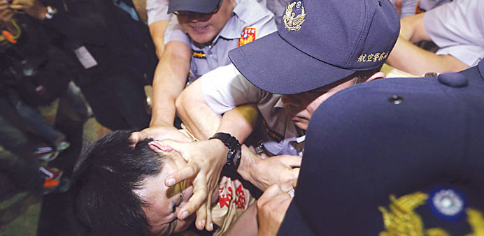 A pro-democracy activist scuffles with police officers at a protest against a visit by Chinese official Zhang Zhijun at the Taoyuan International Airp