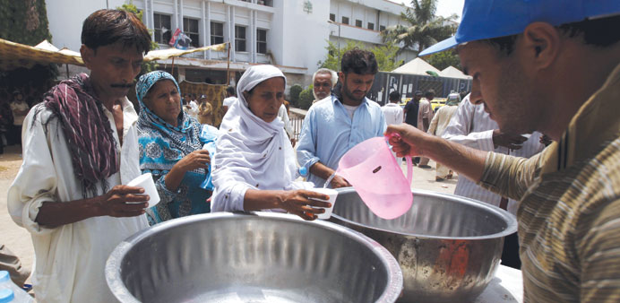 People receive drinking water from a volunteer at a stall, set up outside Jinnah Postgraduate Medical Centre during intense hot weather in Karachi yes