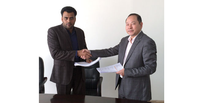 Huang (right) and Chakkarath shaking hands after signing the agreement for the opening of a Grand Mart at Dragon Mart at Barwa Commercial Avenue.