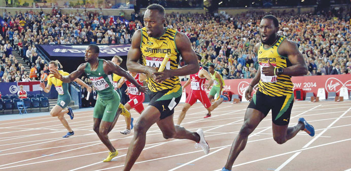 Usain Bolt of Jamaica (centre) gets the baton from teammate Nickel Ashmeade (right) for the final leg of a heat of the menu2019s 4x100m relay at the Commo