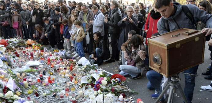 People gather in front of a memorial along a police cordon set-up close to the Bataclan concert hall
